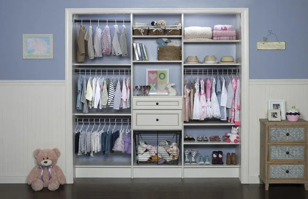 Nursery closet with baby clothes hanging above open cubbies and baskets by Famille Closets
