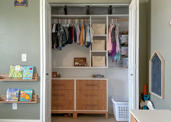 Kids’ reach-in closet with hanging, shelves and a wood dresser by Famille Closets