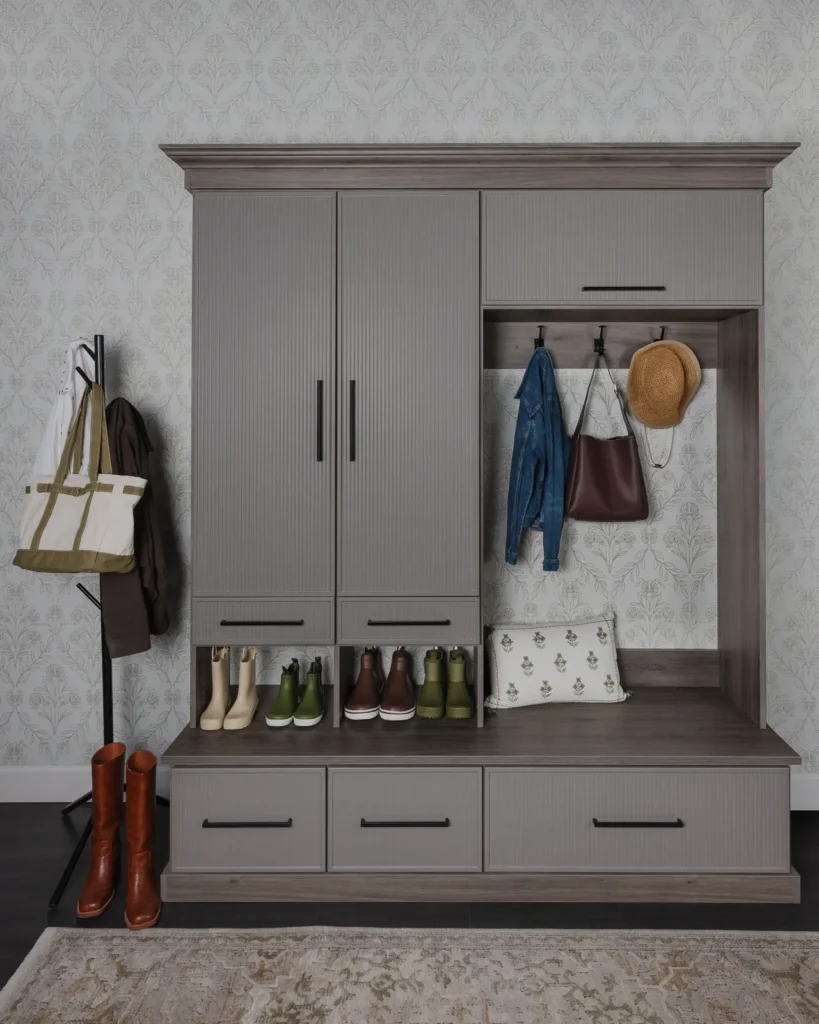 Custom grey mudroom locker with tall cabinets, coat hooks, bench and shoe storage
