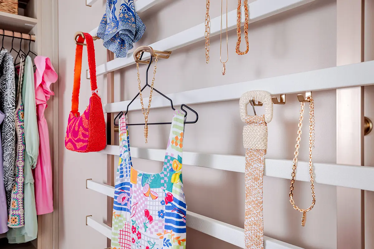 Wall-mounted accessory rail system with gold hooks for bags, belts and jewellery