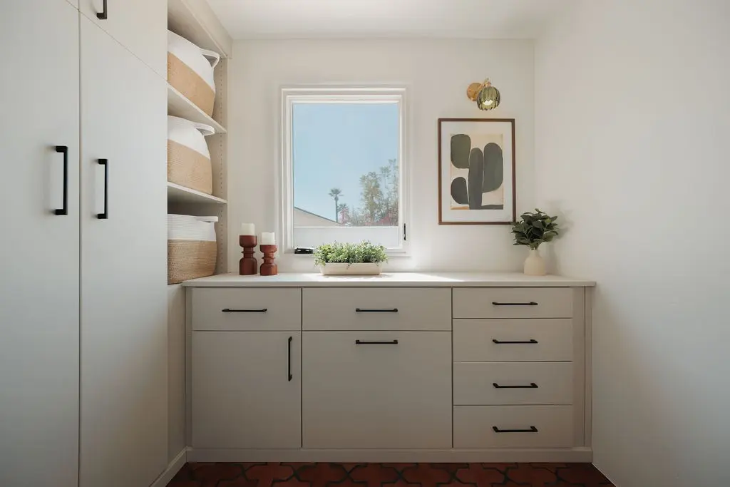 Vintage finish laundry room cabinets with drawers and a countertop under a window