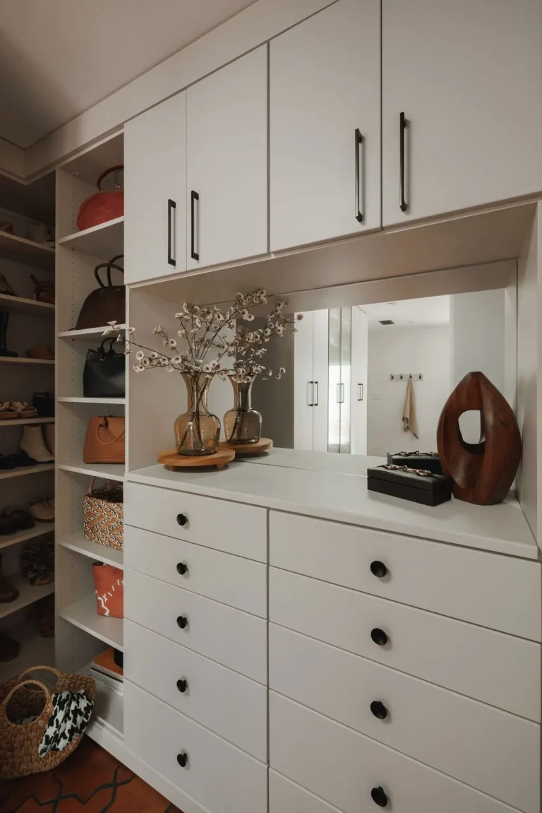 Vintage finish walk-in closet with upper cabinets, a mirror and a drawer bank