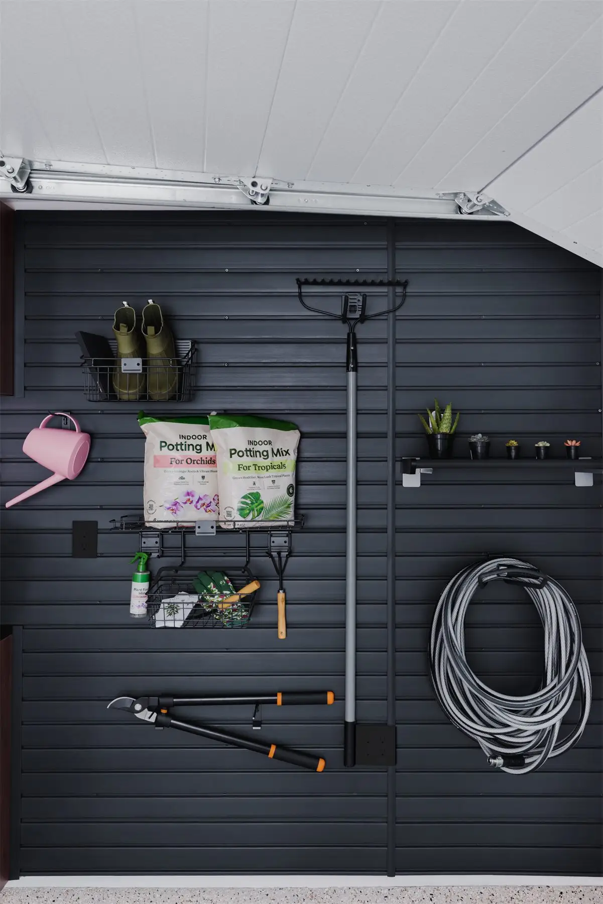 Black slatwall with garden tools by Famille Closets