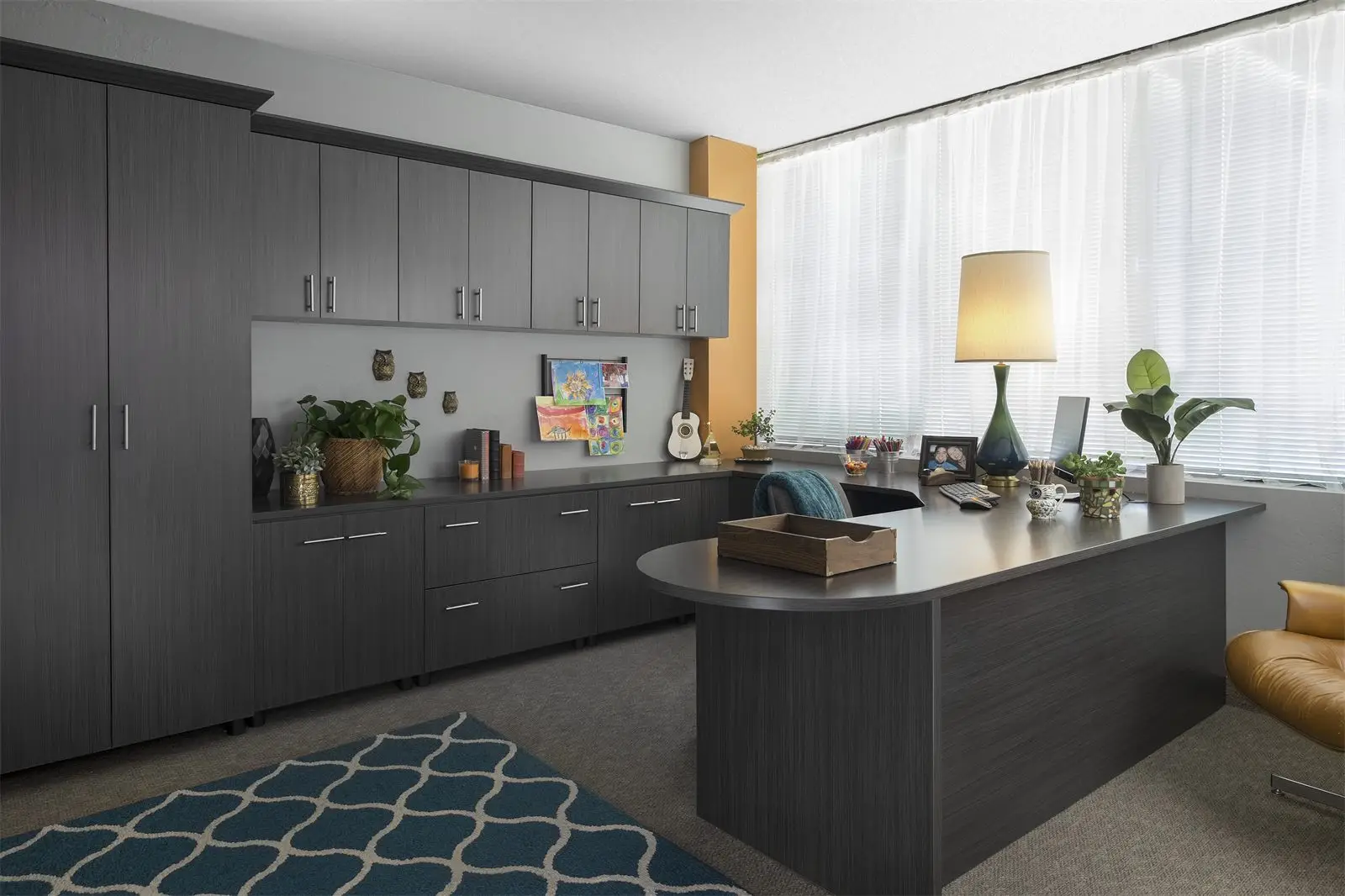 Dark woodgrain office with tall wall cabinets and a curved desk by Famille Closets