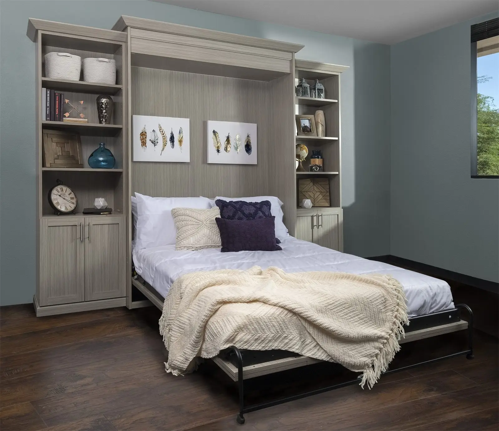 Grey Murphy bed open in a guest room with shelving and cabinets on both sides by Famille Closets