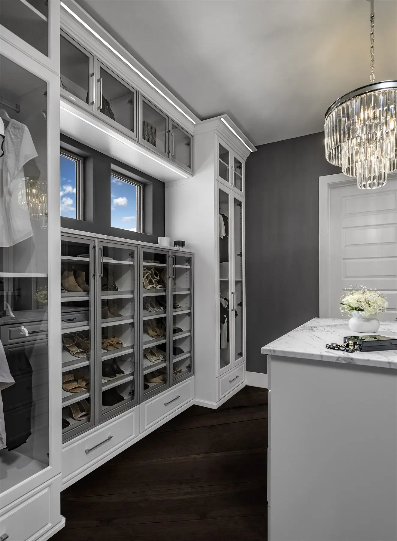 White walk-in closet with clear glass doors by Famille Closets