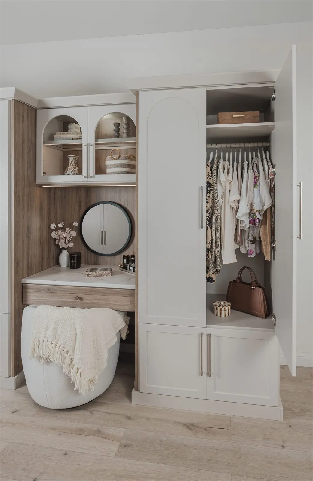 Wardrobe and vanity with one door open to show hanging clothes by Famille Closets