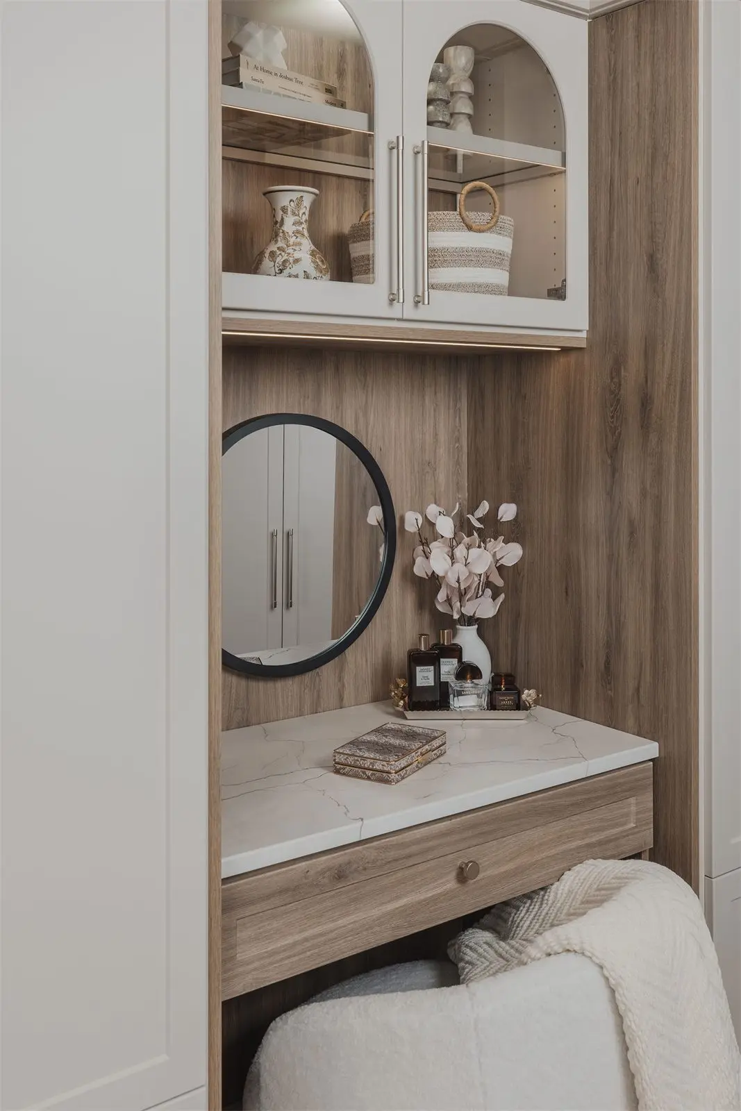 Built-in vanity with a round mirror between two wardrobes by Famille Closets